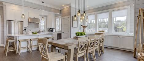 A modern kitchen with white cabinetry, a central island with stools, and pendant lighting.