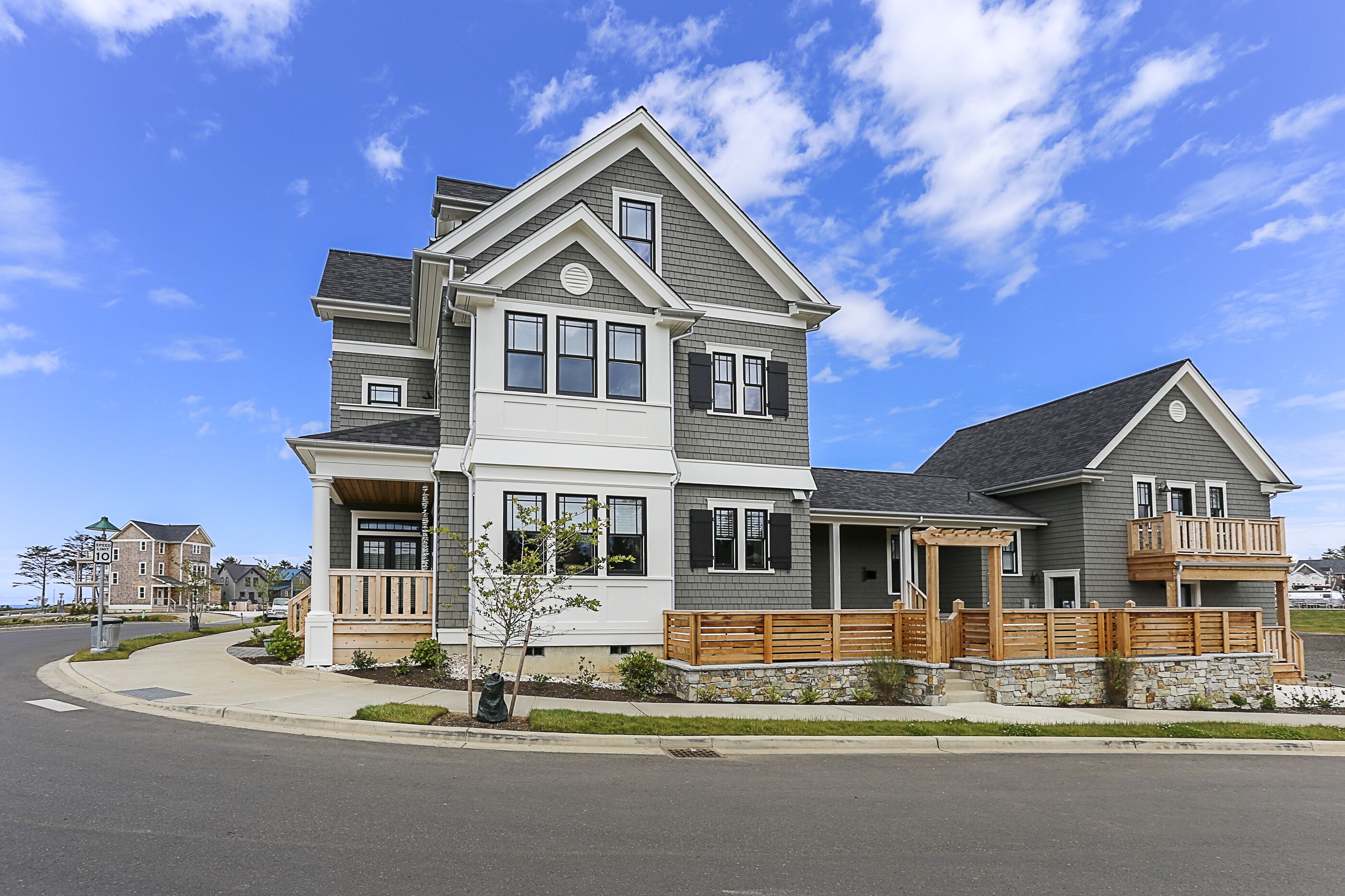 A two-story house with a balcony, a covered porch, and a stone foundation.