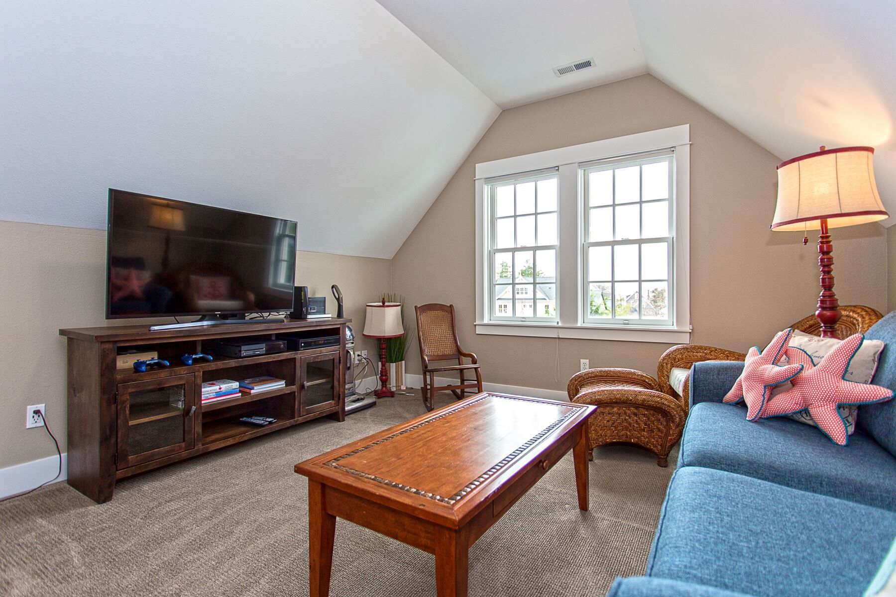 A cozy living room with a television, wooden entertainment unit, and a blue sofa.