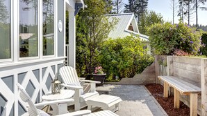 Eine Terrasse mit Adirondack-Stühlen, einer Holzbank und einem Blumentopf.