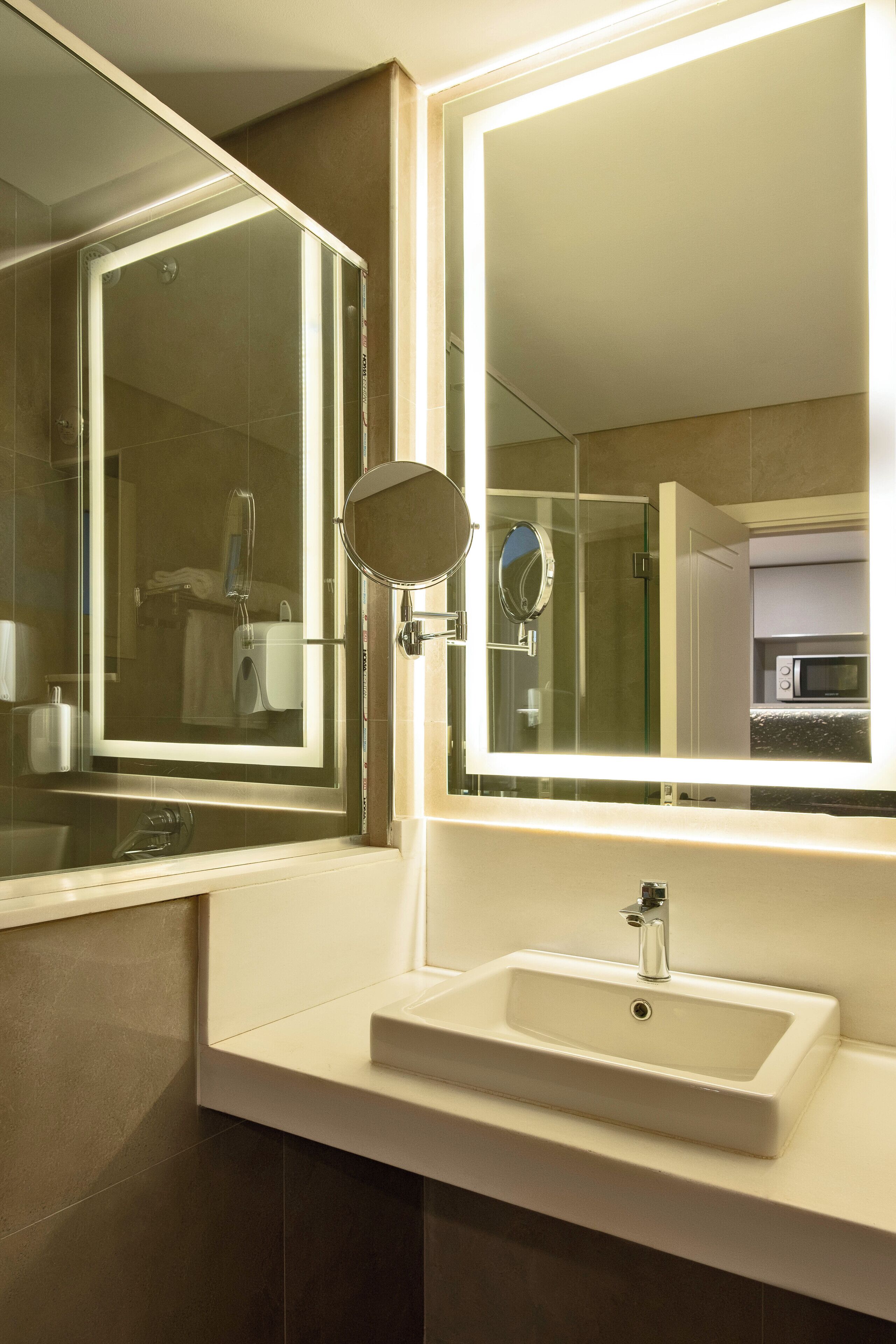 Un baño con un espejo grande, un lavamanos y una ducha.