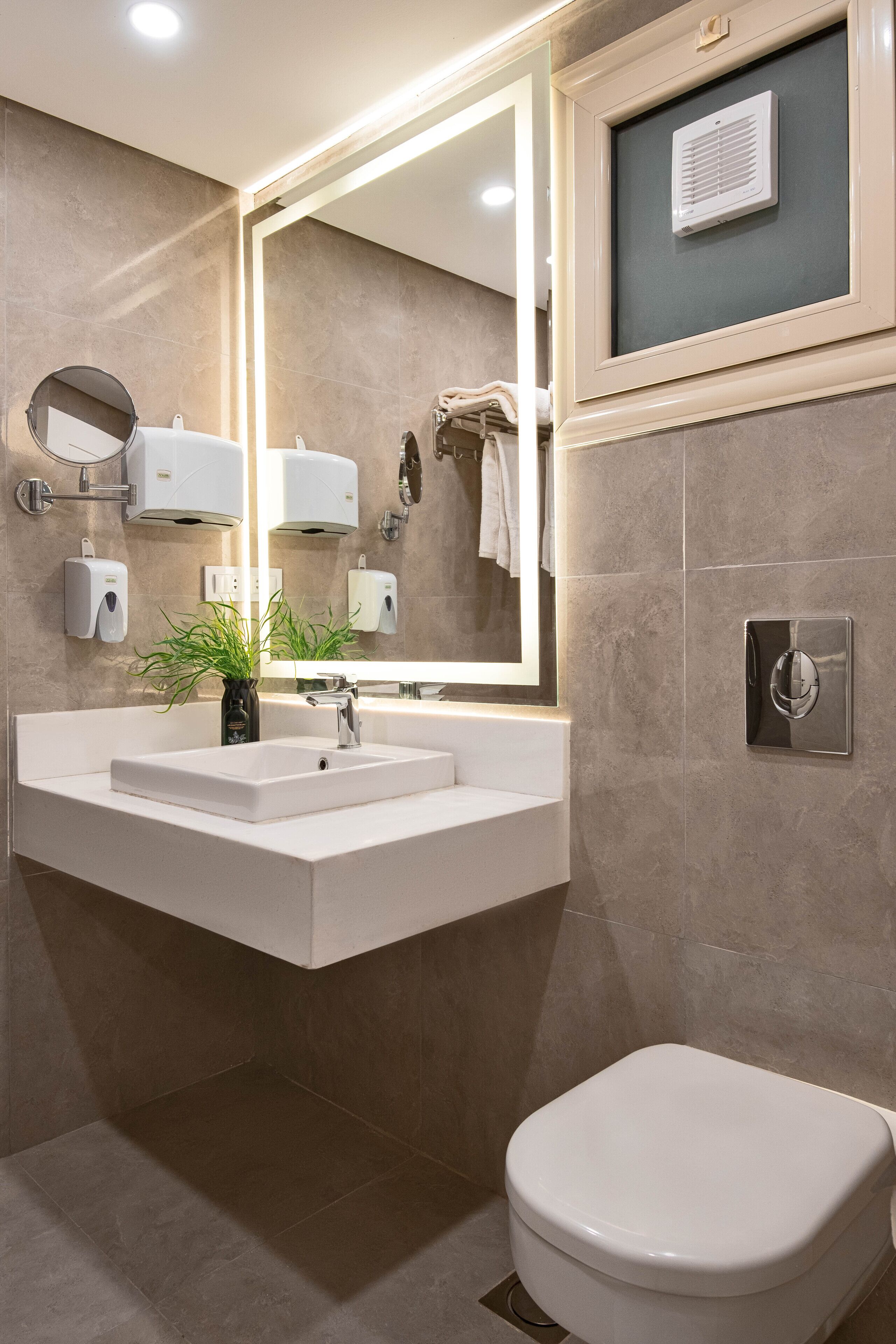 Un bagno moderno con lavandino, specchio e water bianchi.