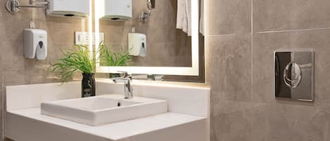 Un bagno moderno con lavandino, specchio e water bianchi.