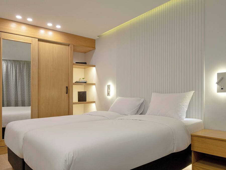 Ein modernes Schlafzimmer mit großem Bett, integriertem Kleiderschrank, Nachttischen und Wandleuchten.