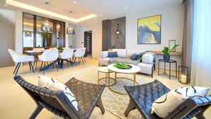 A modern living room with a sofa, two lounge chairs, a dining area with chairs and a table, and a kitchen in the background. - Villa LADY with heated pool, jacuzzi and sauna (Pinezići)