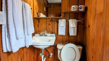 A wooden-paneled bathroom with a white sink, toilet, and towel rack.