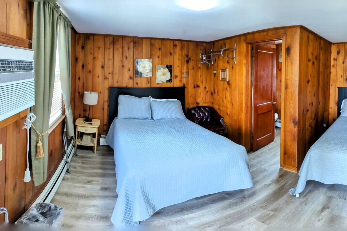 A room with two beds, wooden walls, a TV, and a no-smoking sign.
