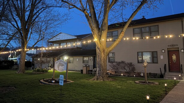 A motel with a signboard, a tree, and string lights. - Riverside Motel (Lewiston)