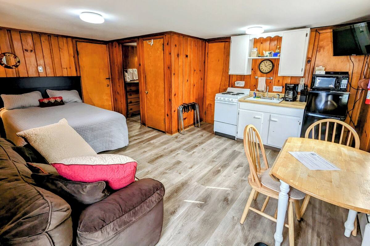 A compact room with a bed, a small kitchenette, and a dining area.