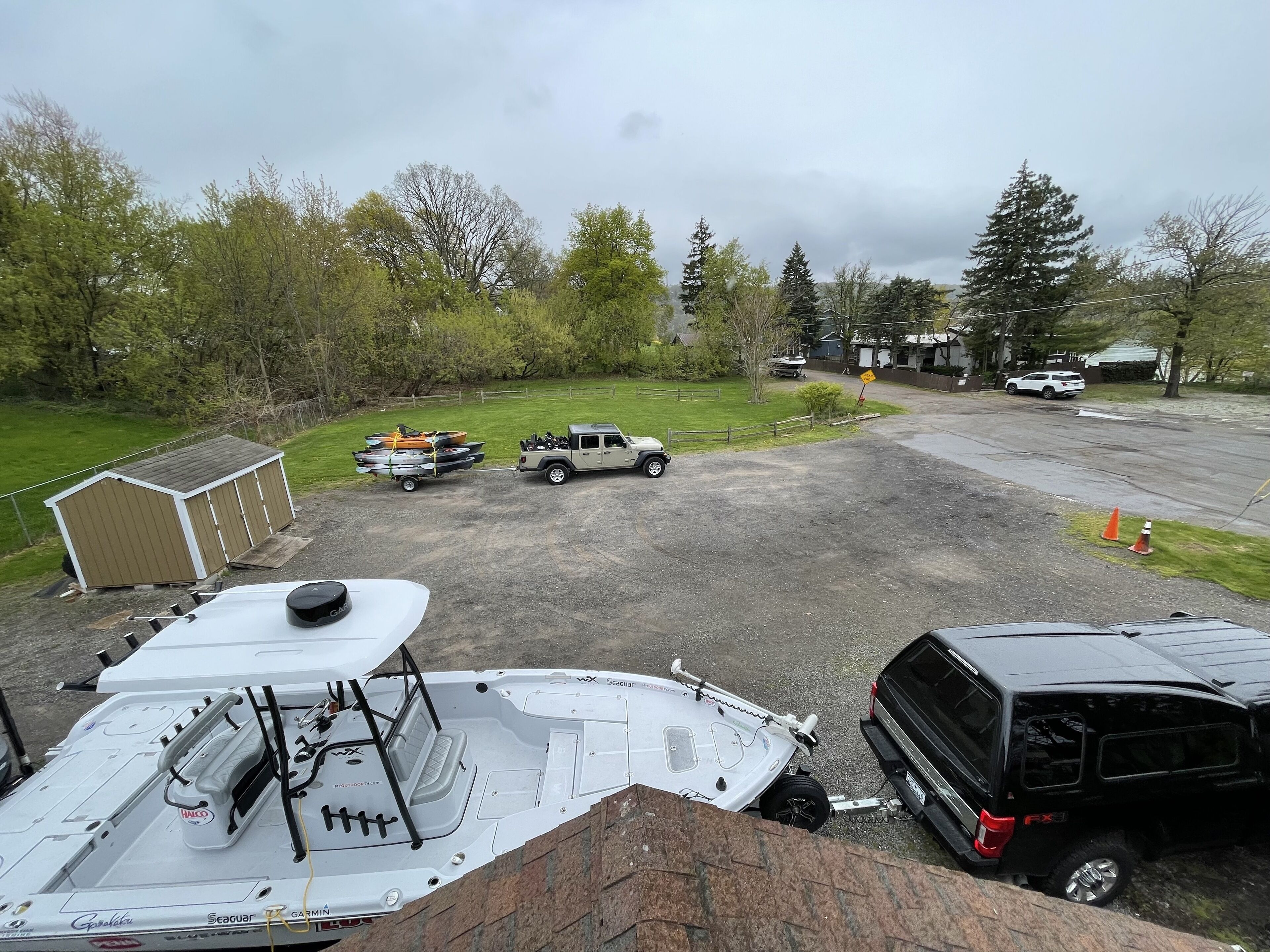 A boat docked at a marina with a trailer carrying kayaks and a Jeep.