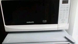 Un refrigerador compacto con un microondas encima.