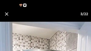 Una ducha con puerta de vidrio, paredes de azulejos y un perchero para toallas.