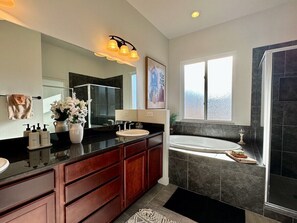 Enjoy a luxurious bathroom experience with a bathtub, double sink vanity, and large mirror.