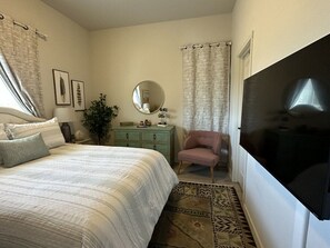 Relax in this serene bedroom with a large bed, dresser, and flat-screen TV.