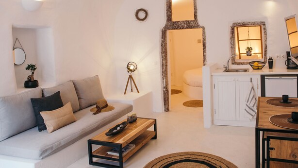 Een moderne woonkamer met een bank, salontafel en een kleine eethoek met een tafel en stoelen.
