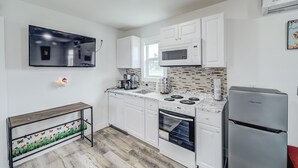 A modern kitchen with white cabinets, a stainless steel refrigerator, a microwave, a stove, and a dishwasher.