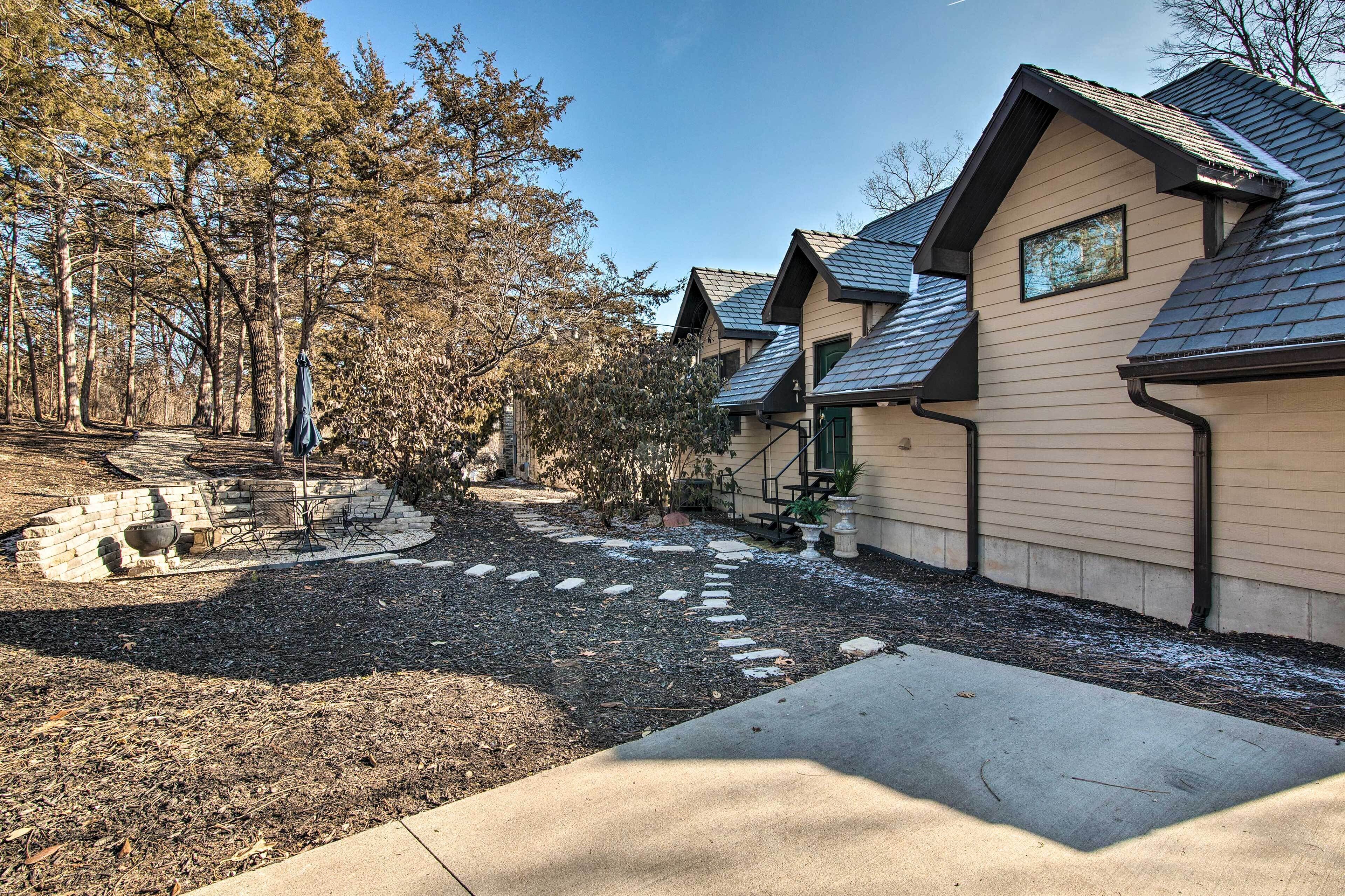 A row of single-story houses with pitched roofs, a stone pathway, and a wooded area.