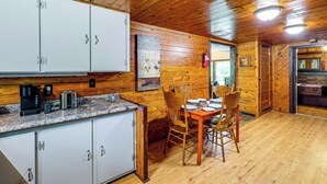 Interior de uma cabana de madeira com área de jantar, cozinha e lareira.