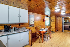 Interior de una cabaña de madera con comedor, cocina y chimenea.