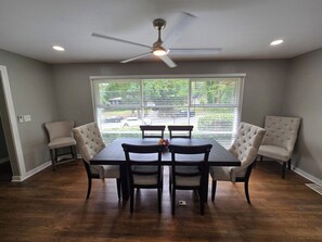 A dining area with a table and chairs, a ceiling fan, and a window with blinds.