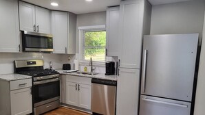 Una cocina moderna con electrodomésticos de acero inoxidable, armarios blancos y un ventanal que proporciona luz natural.