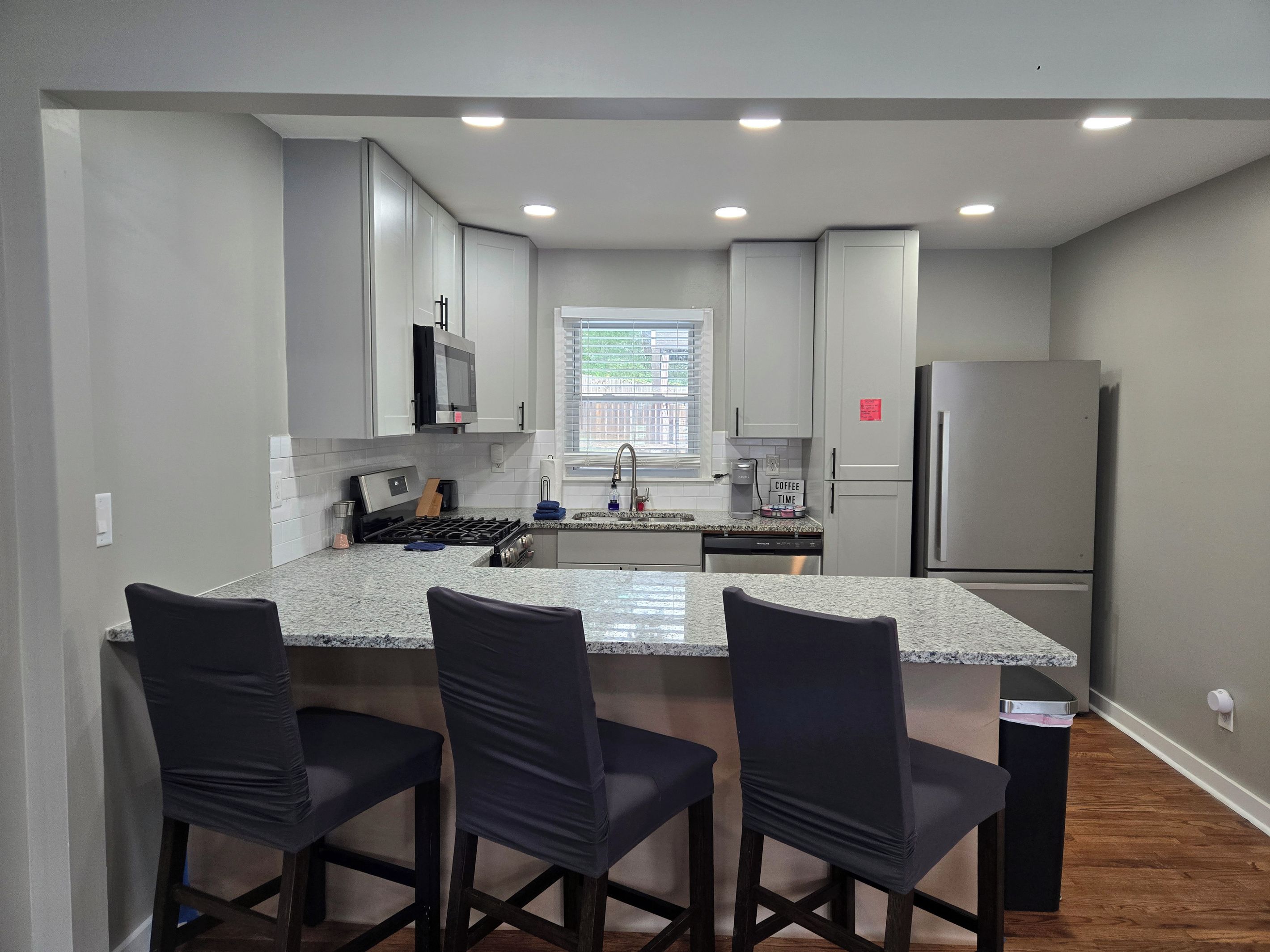 Una cocina moderna con una isla central, electrodomésticos de acero inoxidable y taburetes de bar.