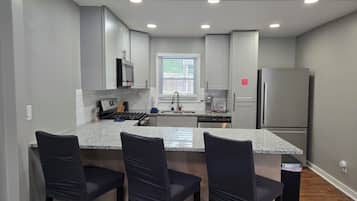 Una cocina moderna con una isla central, electrodomésticos de acero inoxidable y taburetes de bar.