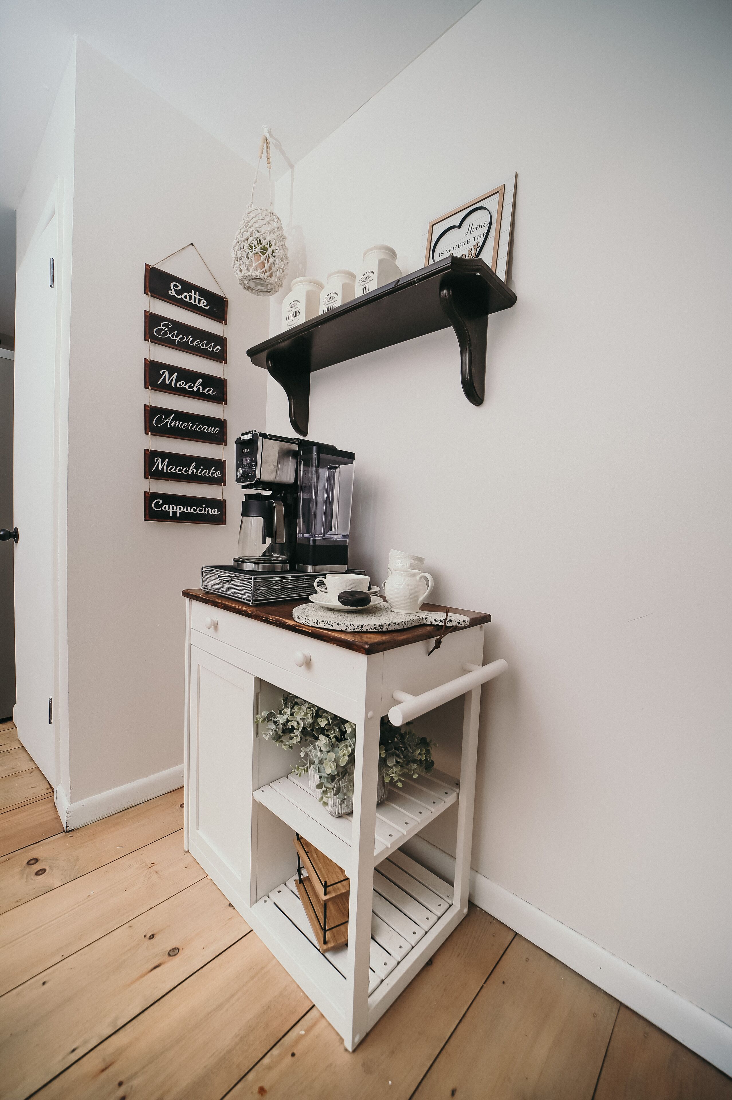 Un coin cuisine équipé d’un espace dédié au café, comprenant une machine à café, des tasses et un panneau indiquant les différents types de café proposés.