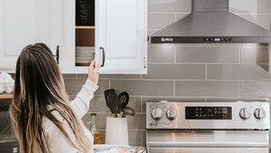 Une cuisine avec des armoires blanches, une hotte en acier inoxydable et un four double.