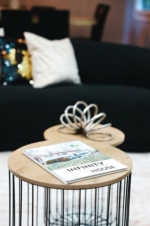 A magazine on a round table with a metal base, a black sofa in the background, and a white pillow. - Only 10min away from Mountain Creek, beautiful spacious house with Mountain View (Municipio de Vernon)