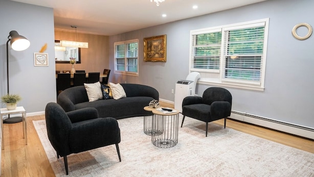 Un salon moderne avec un canapé, deux fauteuils, une table basse et, au fond, un coin repas.