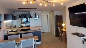 Een moderne keuken met een eethoek, een grote televisie en een trap naar een hoger niveau.