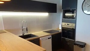 Een moderne keuken met een houten aanrecht, een vaatwasser, een oven en een klok aan de muur.