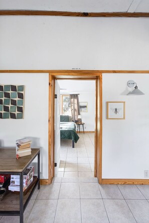 A room with a bed, a table with books, a wall-mounted lamp, and a framed picture. - Kind Of Blue - A Hill Country Cottage (San Marcos)
