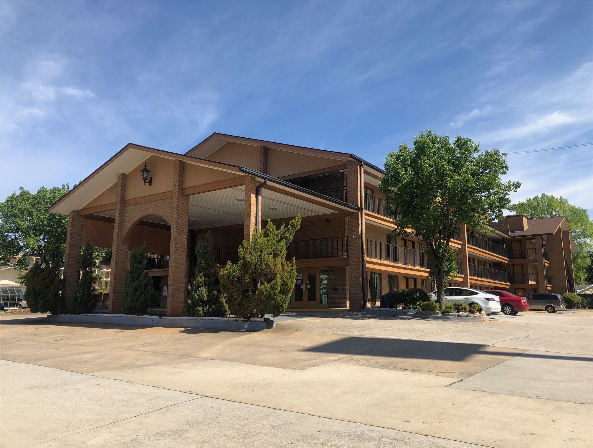 A multi-story hotel with a covered entrance and a parking lot.