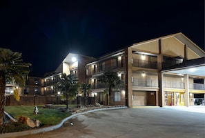 A multi-story hotel with a covered parking area and a well-lit entrance.