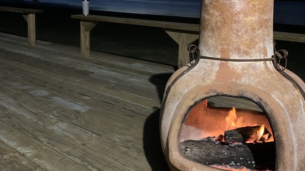 A wood-fired oven on a wooden deck with a lake view at night.