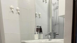 Une salle de bain avec un lavabo blanc, un miroir et des armoires.