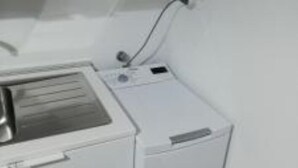 Un espace buanderie compact comprenant un lave-linge et un évier.