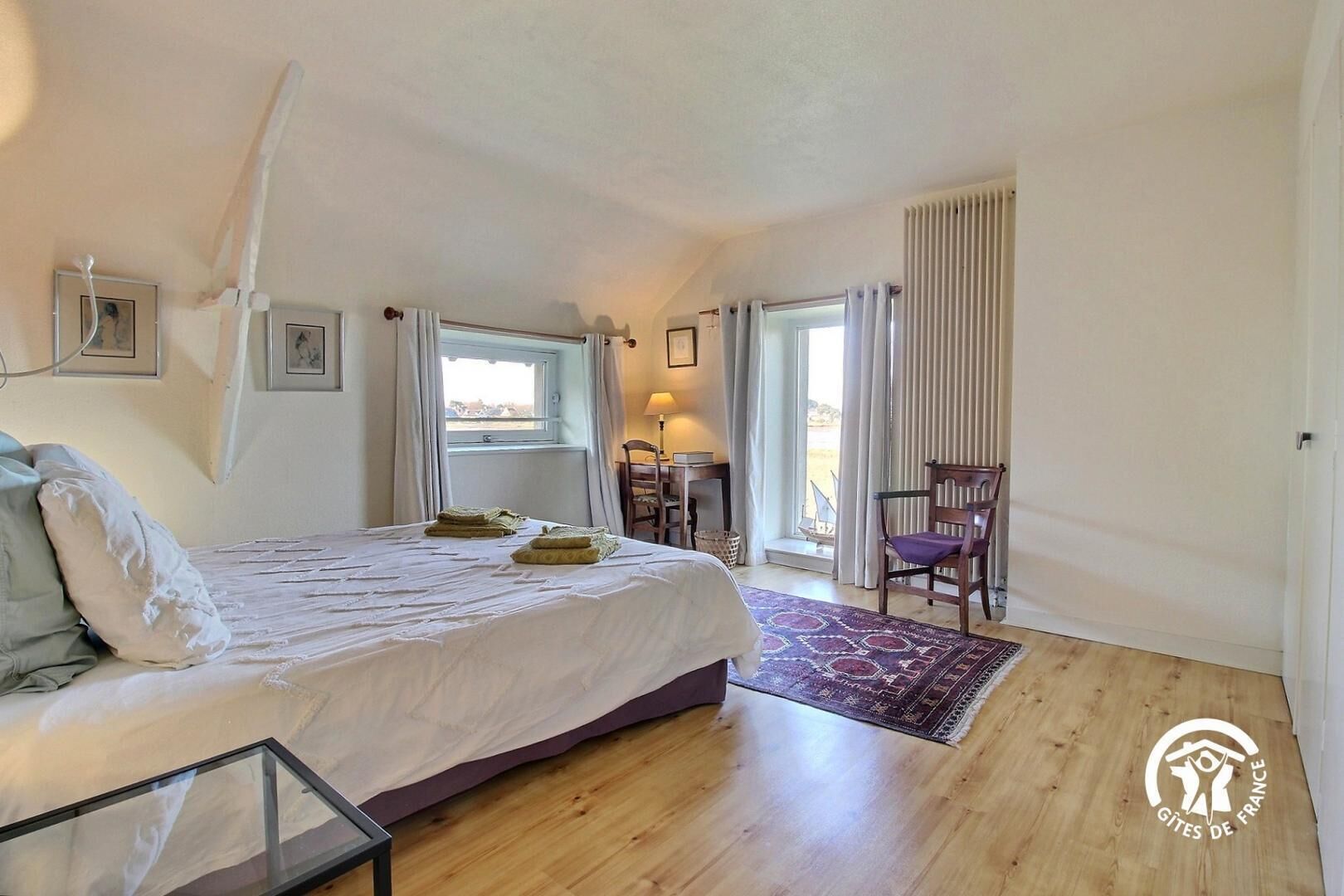 Een slaapkamer met een bed, een bureau, een stoel en uitzicht op de omgeving.