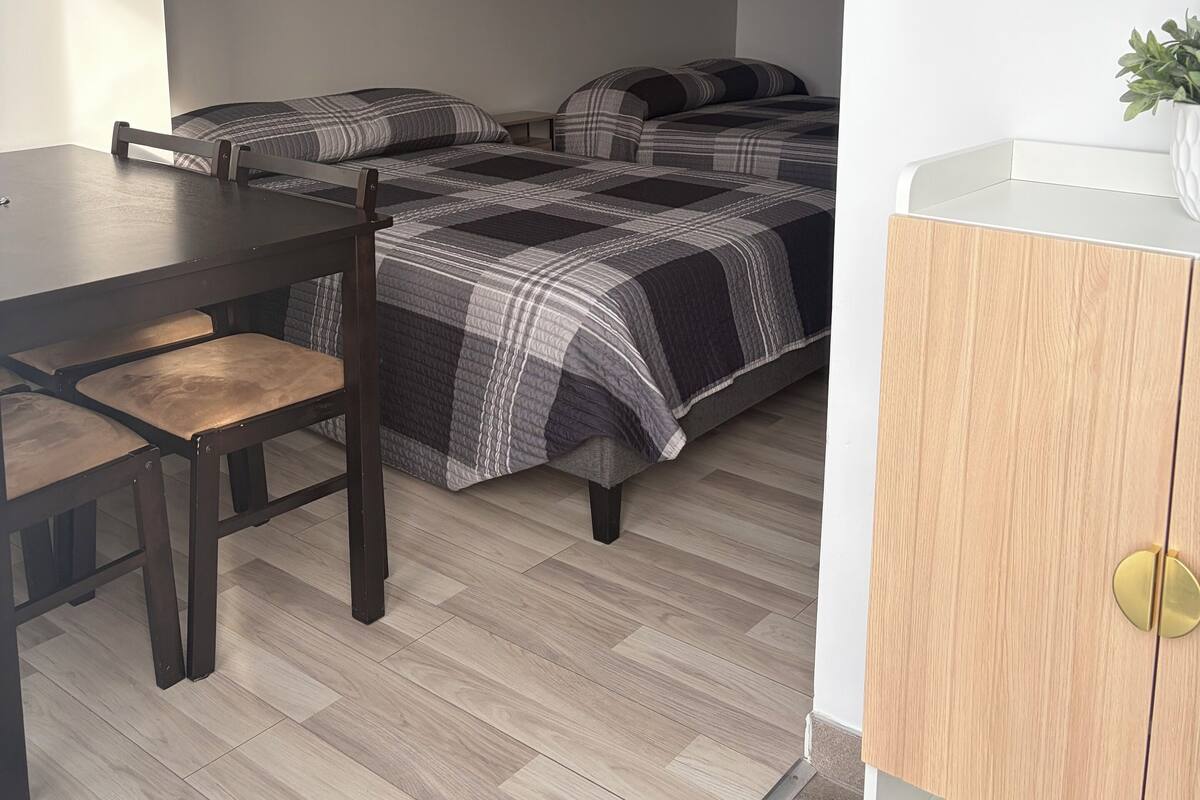 Un dormitorio con cama, televisión, techo de madera y una mesita.