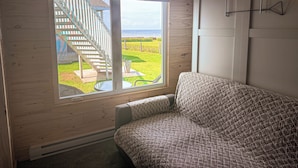 Habitación con un gran ventanal con vistas a una zona verde y una escalera que sale al exterior.