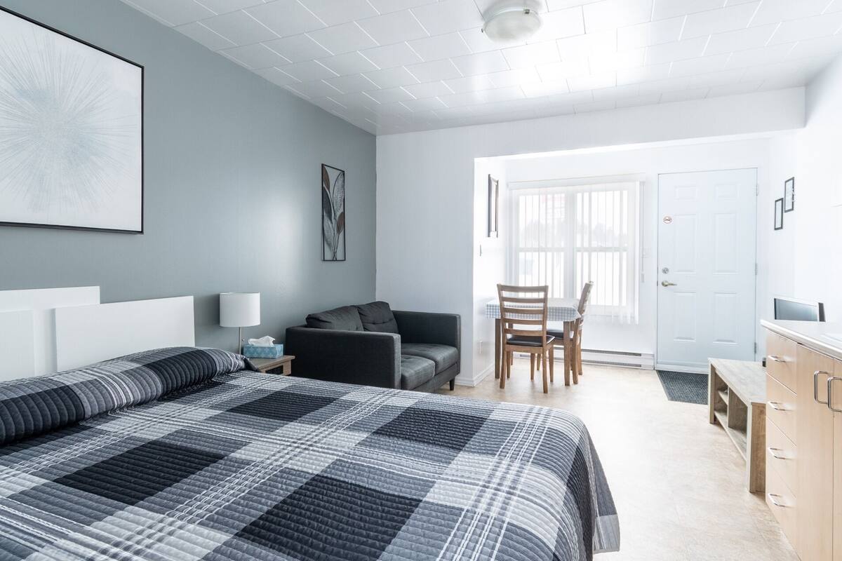 Un dormitorio con una cama grande, un escritorio, una silla y una puerta que da a otra habitación.