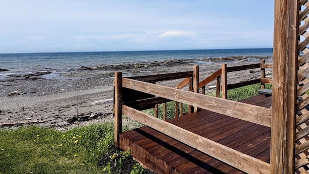 Una terraza de madera con vista a la costa rocosa y al océano.