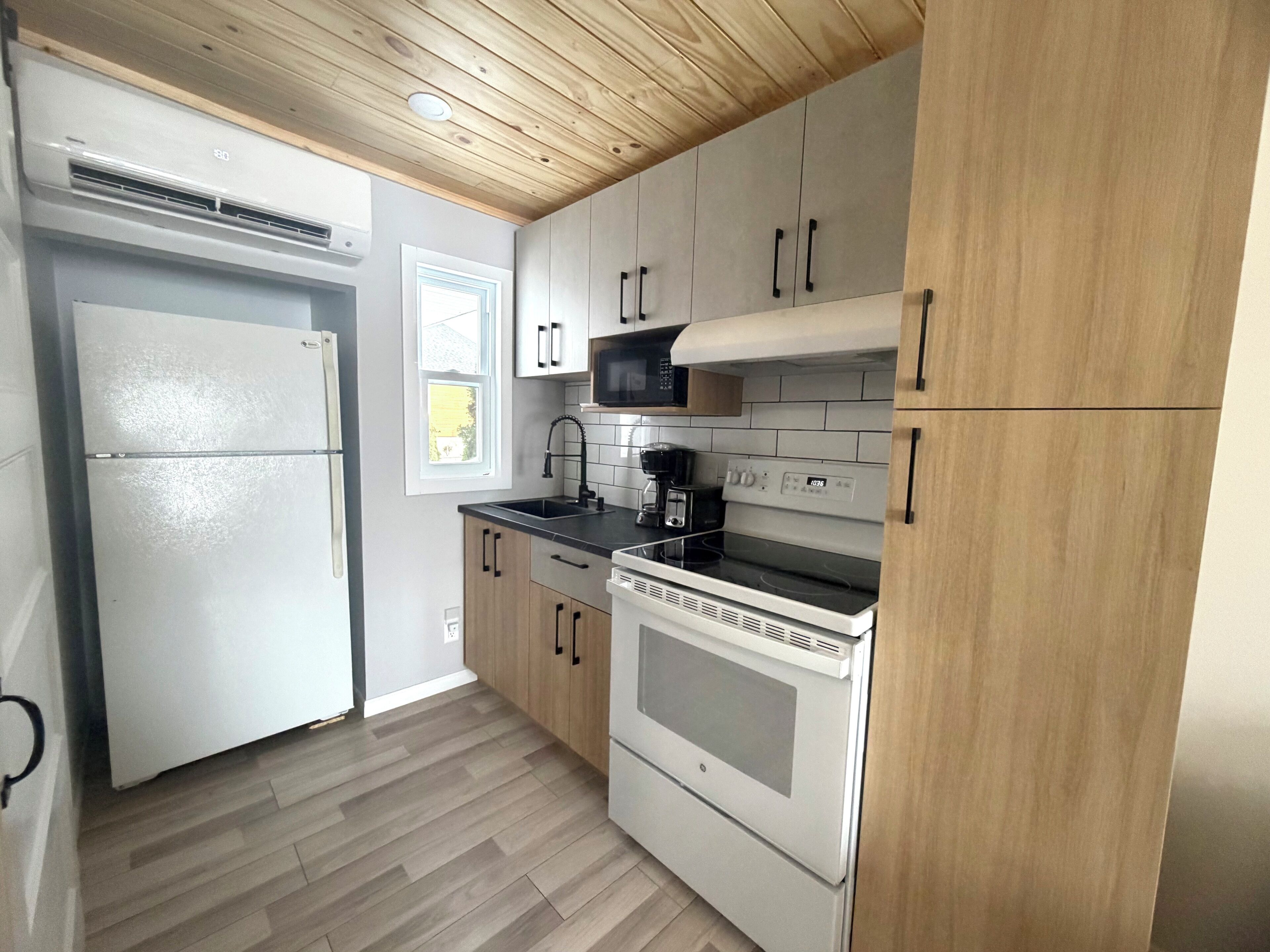 A compact kitchen with a refrigerator, microwave, stove, and sink.
