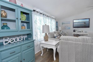 Coastal-themed living space with a sofa, flat-screen TV, and decorative accents.