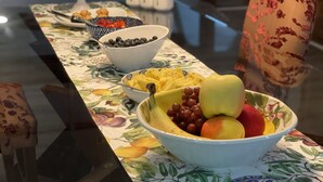 A table with a floral tablecloth, bowls of fruit, and a decorative chair. - Room 2 - The Inn at Dirickson Creek (Frankford)
