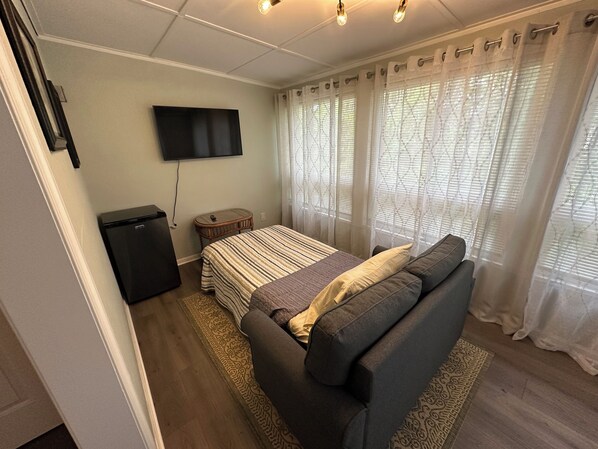 Ein Schlafzimmer mit einem Bett, einem Fernseher, einem kleinen Tisch und einem Kleiderschrank.