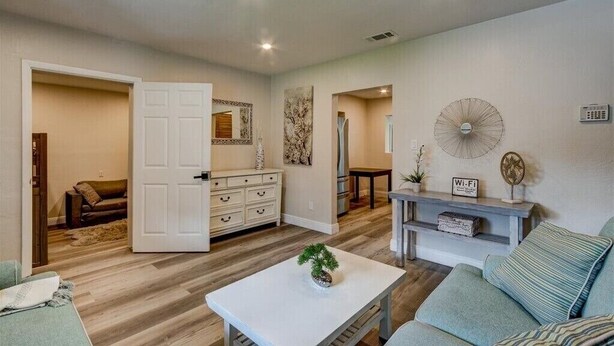 A spacious living room with a sofa, coffee table, and a dining area with a fan.