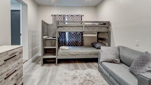 A bunk bed room with a desk, a sofa, and a white furry rug.